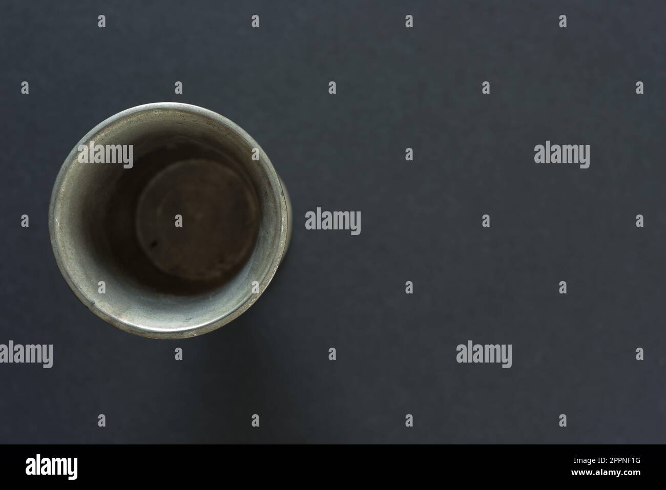 tazza o contenitore metallico, fotografato dall'alto, su fondo di cartone grigio scuro Foto Stock