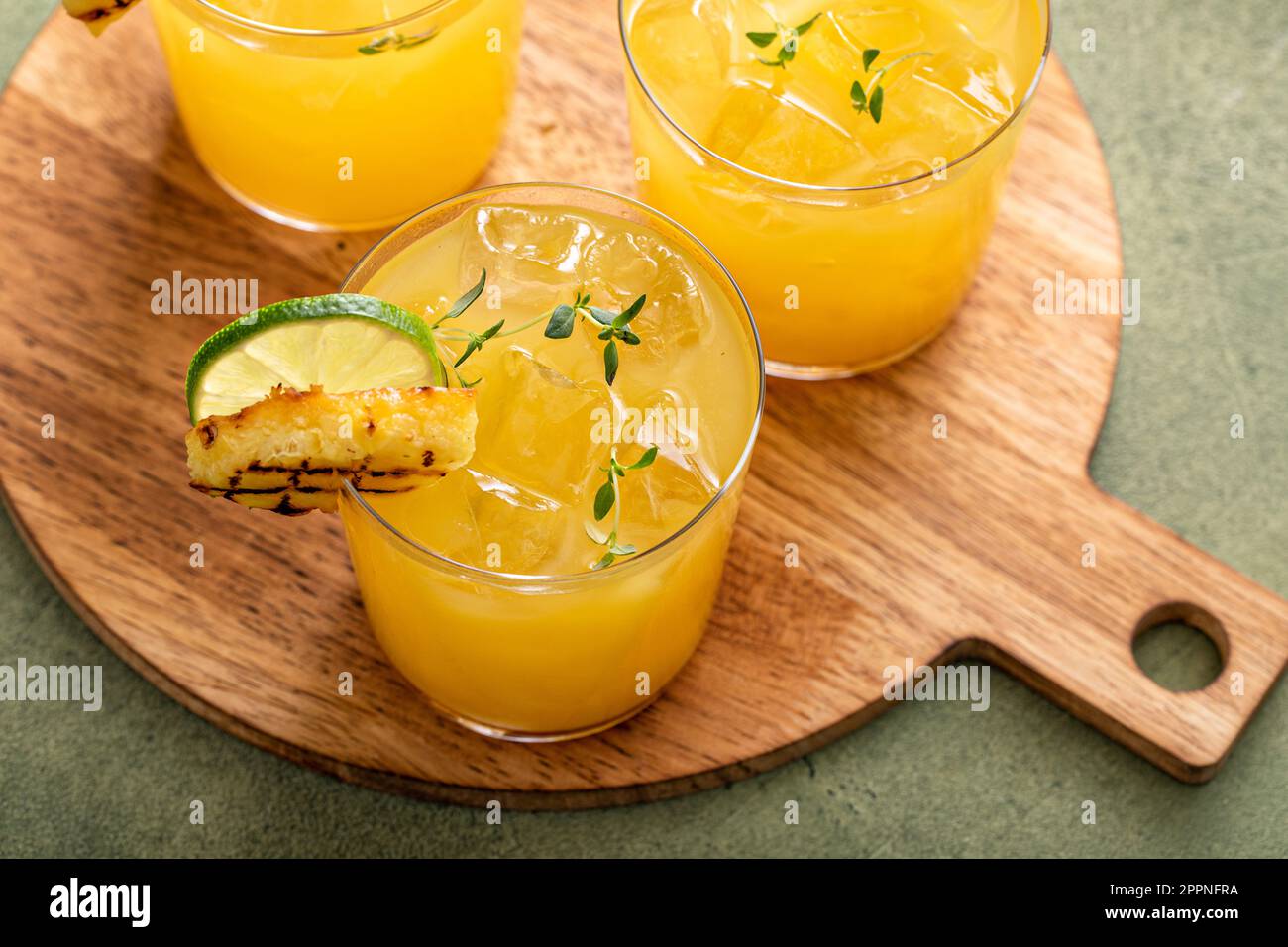 margarita di ananas alla griglia guarnita con spicchi di lime e timo Foto Stock