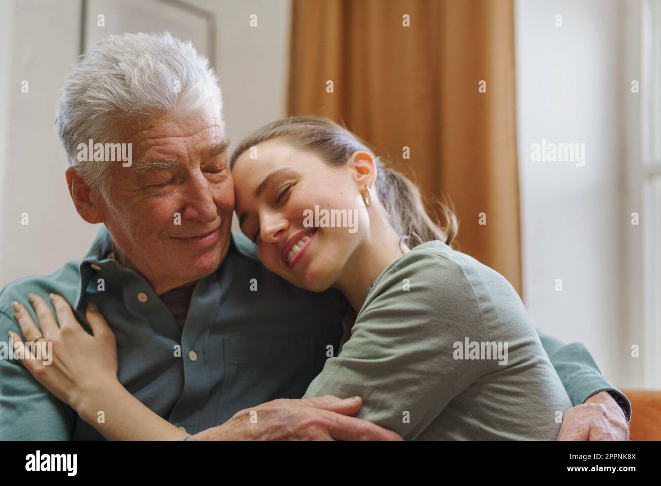 Nipote abbraccia suo nonno nella loro casa. Foto Stock