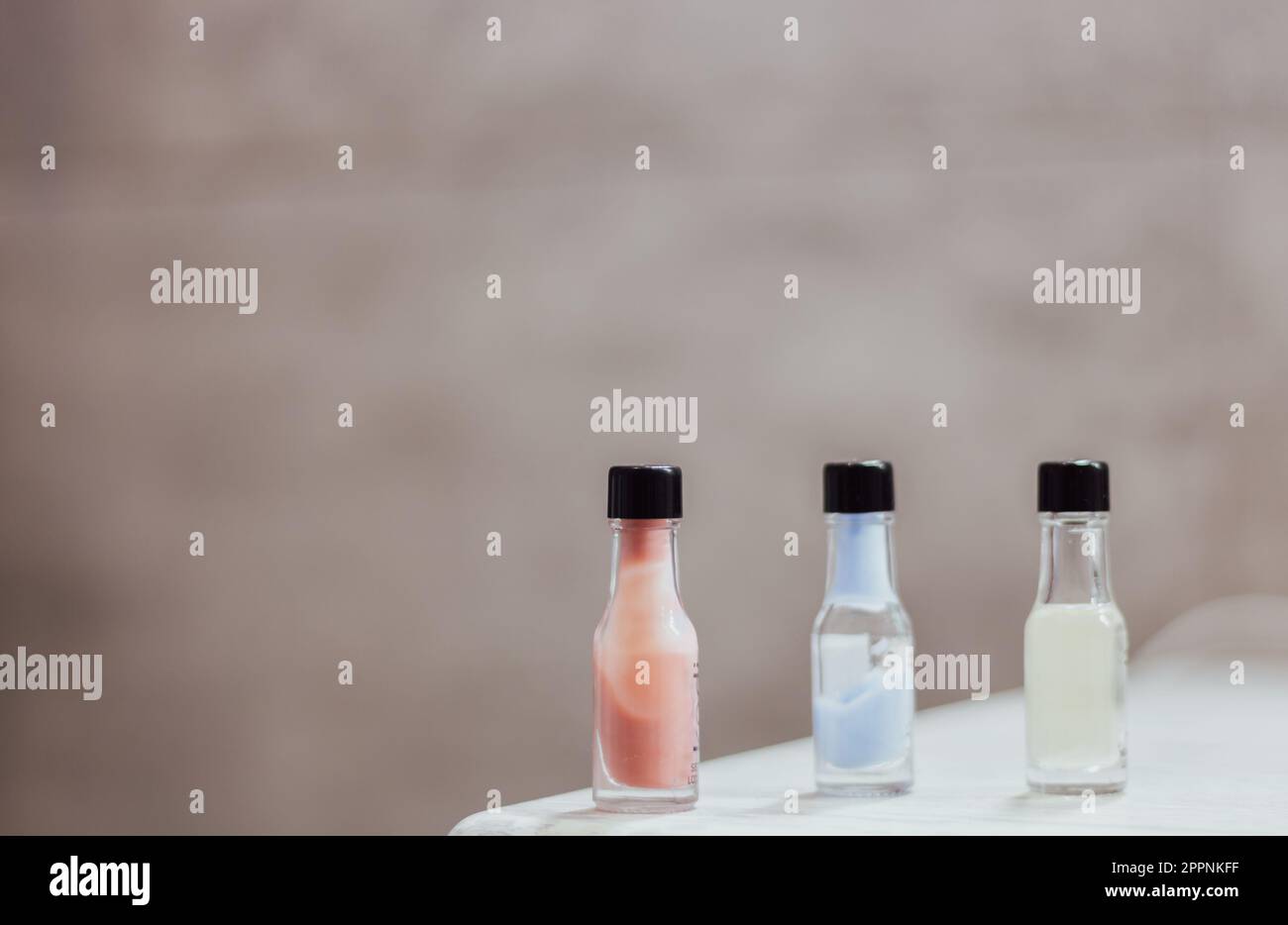 Tre bottigliette di crema colorata in fila con spazio copia. Prodotto benessere sul tavolo. Bagno. Prodotto cosmetico. Stili di vita sani. Foto Stock
