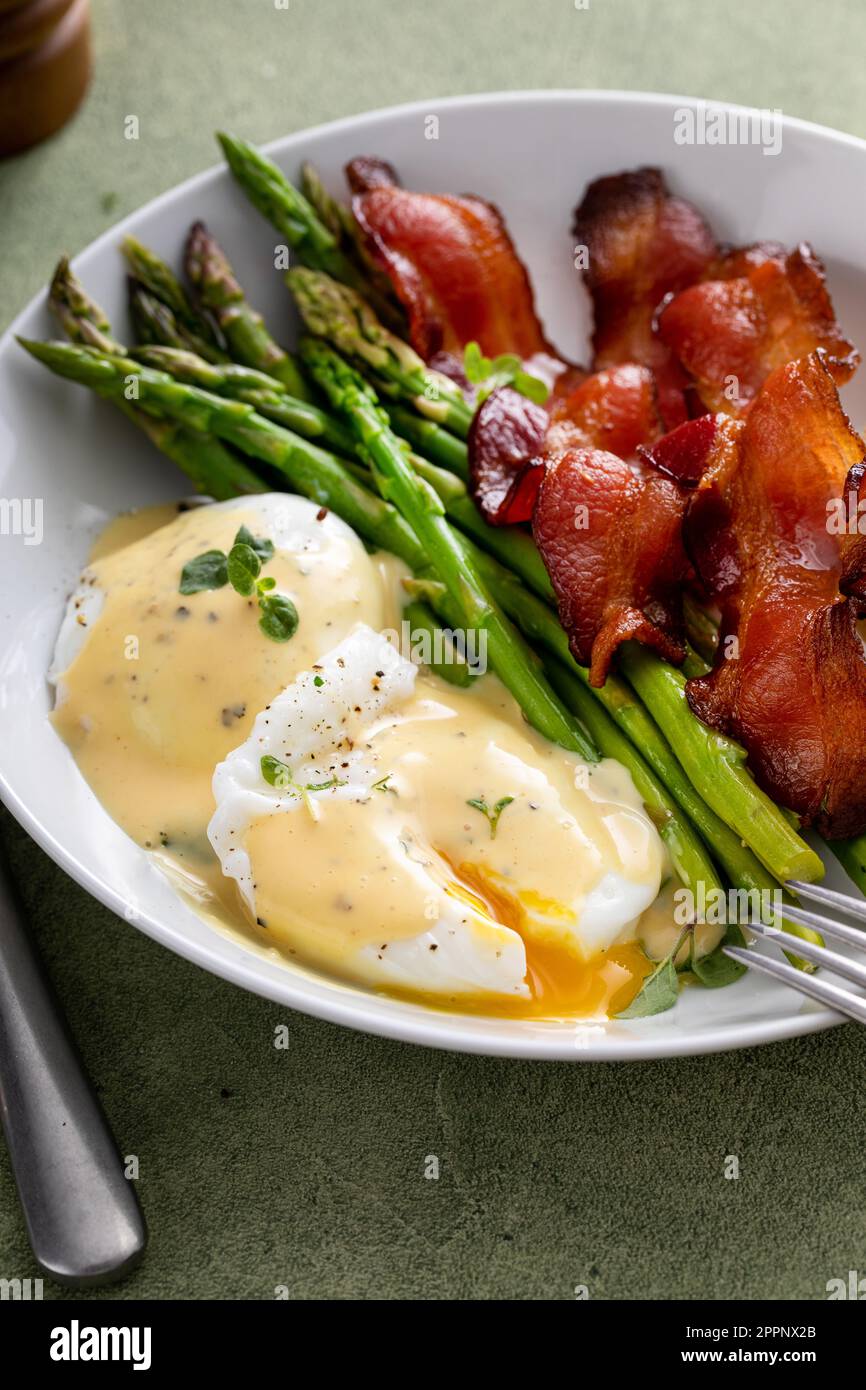 Colazione sana con uova in camicia, pancetta e asparagi serviti con salsa di hollandaise Foto Stock