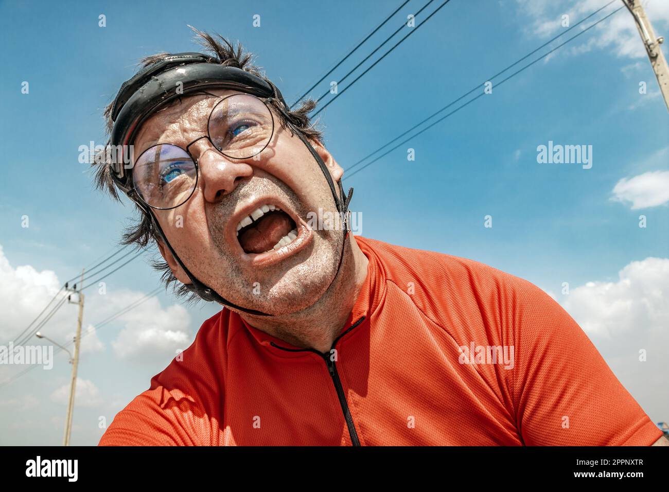 Un ciclista esausto è in bicicletta sotto un cielo blu Foto Stock