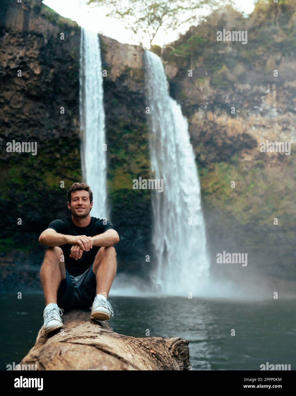 Uomo in piedi di fronte alla cascata di Wailua a Kauai, Hawaii. Foto di alta qualità. Situato nel Parco Statale del Fiume Wailua. Viaggi hawaiani Foto Stock