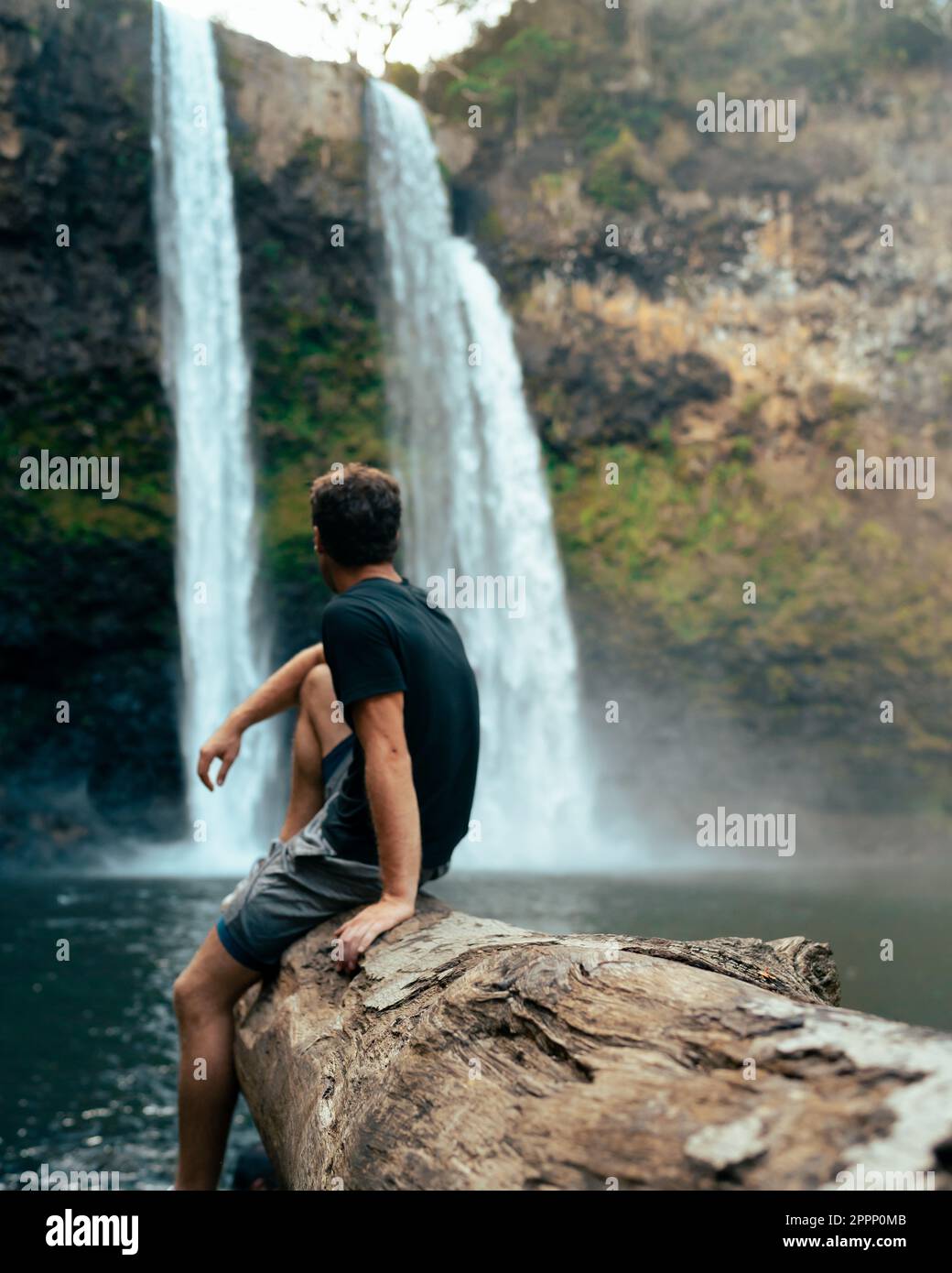 Uomo in piedi di fronte alla cascata di Wailua a Kauai, Hawaii. Foto di alta qualità. Situato nel Parco Statale del Fiume Wailua. Viaggi hawaiani Foto Stock