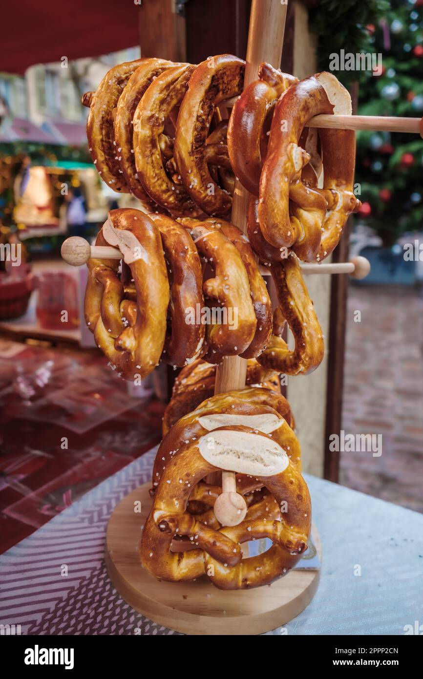 Il pretzel o bretzel è un tipo di pasta da forno che viene comunemente formata in un nodo. Pretzel impilati su uno stand di legno in una resta francese Foto Stock