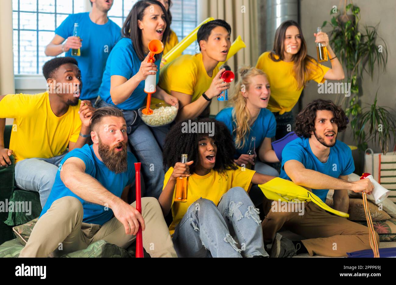 Tifosi di calcio amici tifosi allietare e guardare la partita di calcio a casa Intenational - Gruppo giovani con t-shirt multicolor divertirsi wi Foto Stock