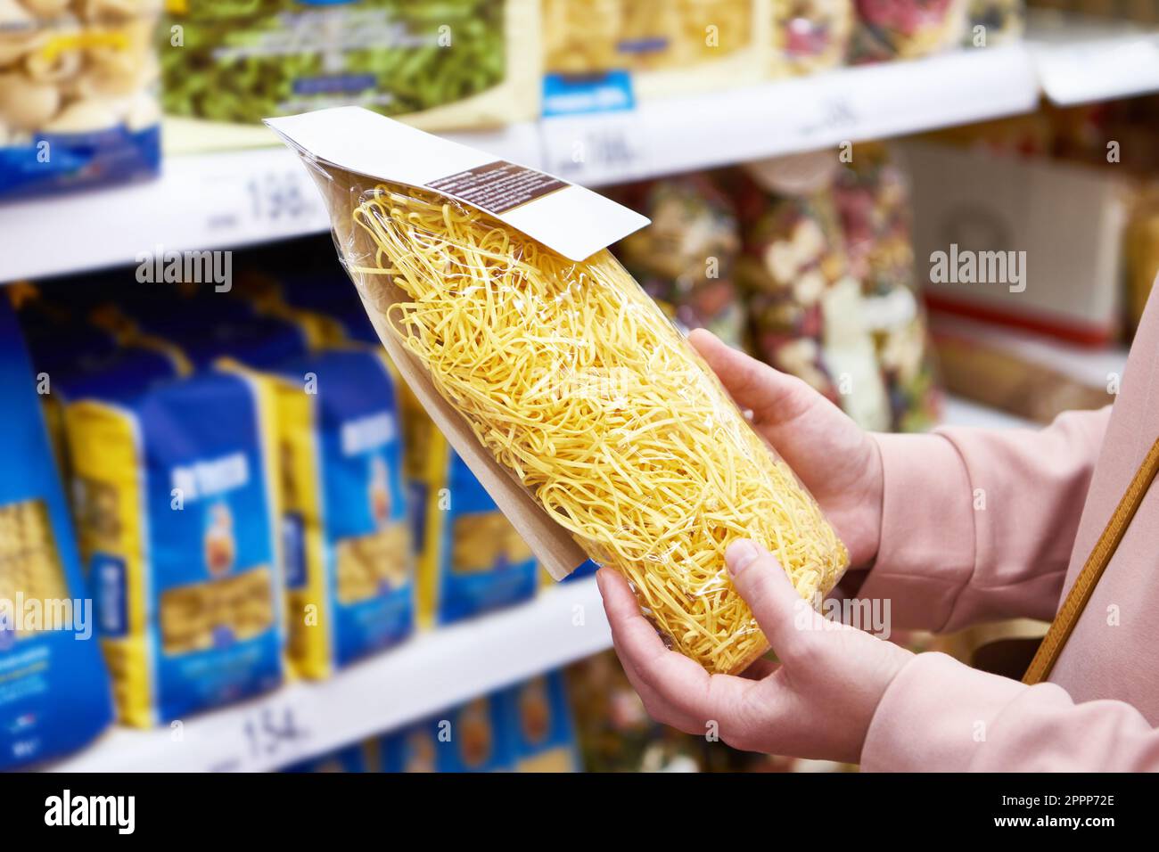 Donna acquirente con una confezione di pasta a shop Foto Stock