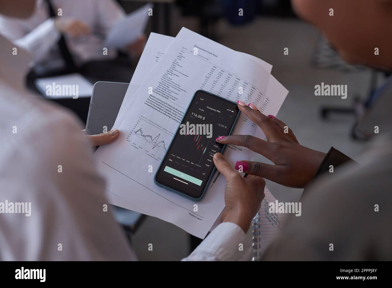 Primo piano dei colleghi che esaminano i grafici finanziari sullo schermo dello smartphone e discutono del mercato azionario Foto Stock