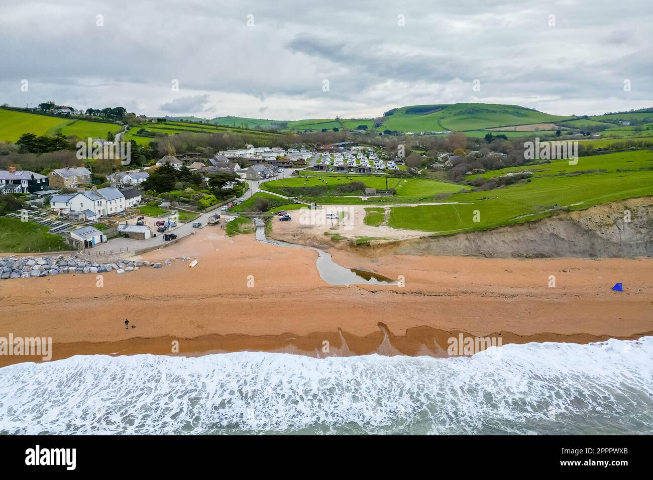 Seatown, Dorset, Regno Unito. 24th aprile 2023. Vista dall'aria della spiaggia, del fiume Winniford e del villaggio di Seatown, sulla costa del Dorset Jurassic. Nel 2022, la tempesta fognaria trabocca 500 metri nell'entroterra accanto al fiume Winniford presso gli impianti di trattamento delle acque reflue di Chideock di proprietà di Wessex Water, (numero di autorizzazione: 401068) ha versato 35 volte per un totale di 363,50 ore, scaricando nel fiume. (Fonte: https://theriverstrust.org/key-issues/sewage-in-rivers) Picture Credit: Graham Hunt/Alamy Live News Foto Stock