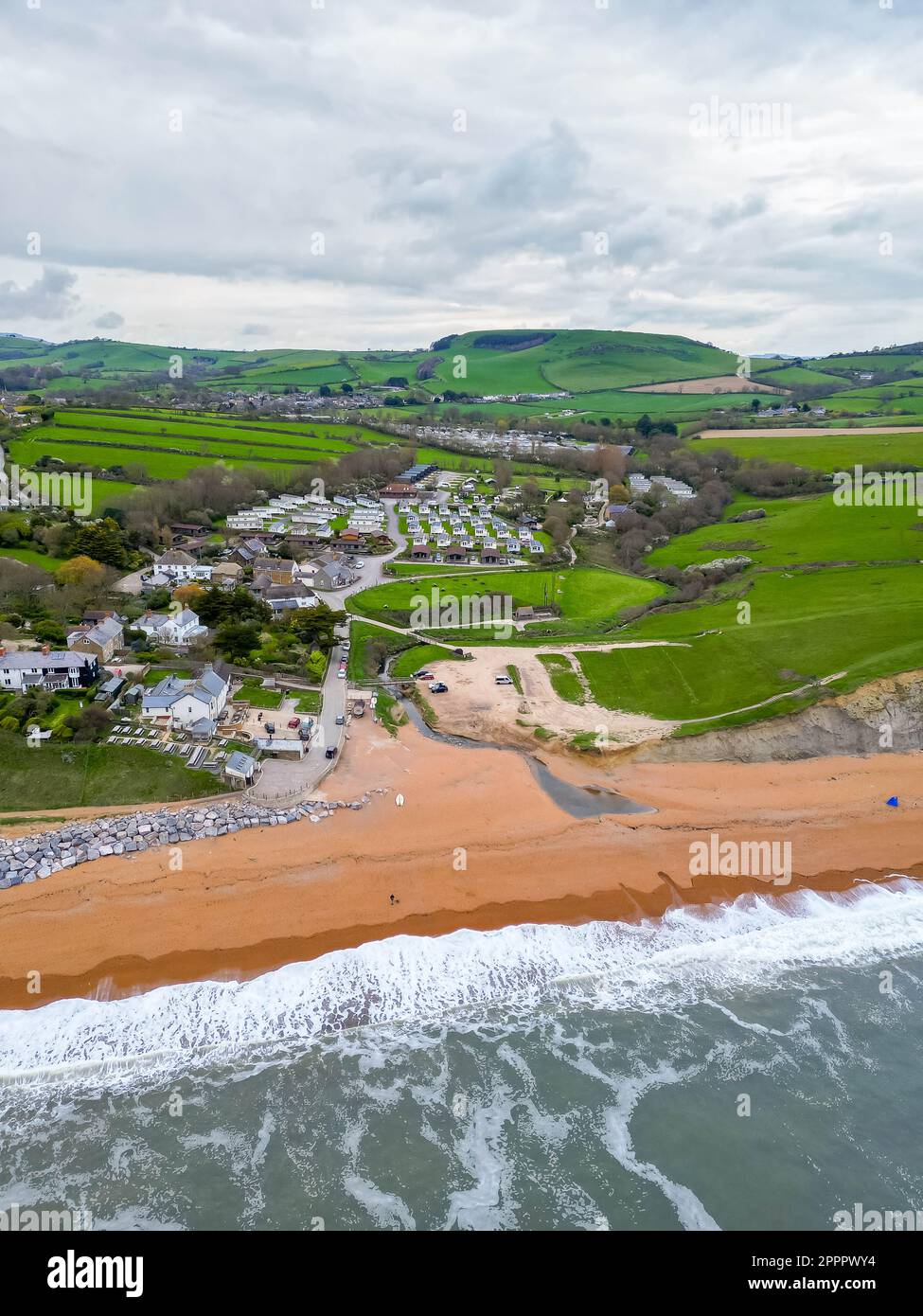 Seatown, Dorset, Regno Unito. 24th aprile 2023. Vista dall'aria della spiaggia, del fiume Winniford e del villaggio di Seatown, sulla costa del Dorset Jurassic. Nel 2022, la tempesta fognaria trabocca 500 metri nell'entroterra accanto al fiume Winniford presso gli impianti di trattamento delle acque reflue di Chideock di proprietà di Wessex Water, (numero di autorizzazione: 401068) ha versato 35 volte per un totale di 363,50 ore, scaricando nel fiume. (Fonte: https://theriverstrust.org/key-issues/sewage-in-rivers) Picture Credit: Graham Hunt/Alamy Live News Foto Stock