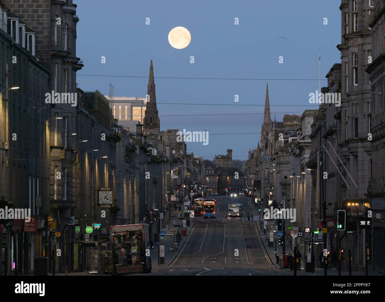 Guardando lungo Union Street nel centro della città di Aberdeen prima dell'alba con una Luna piena (Luna Rosa di aprile) ambientata tra due spirali della Chiesa nel West End Foto Stock