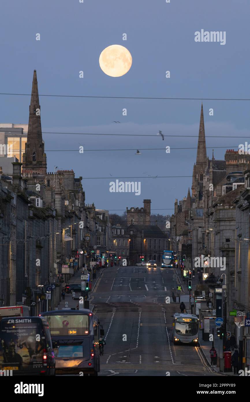 Guardando verso ovest lungo Union Street ad Aberdeen prima dell'alba con la Luna piena (Luna Rosa) che si trova tra due spirali della Chiesa Foto Stock