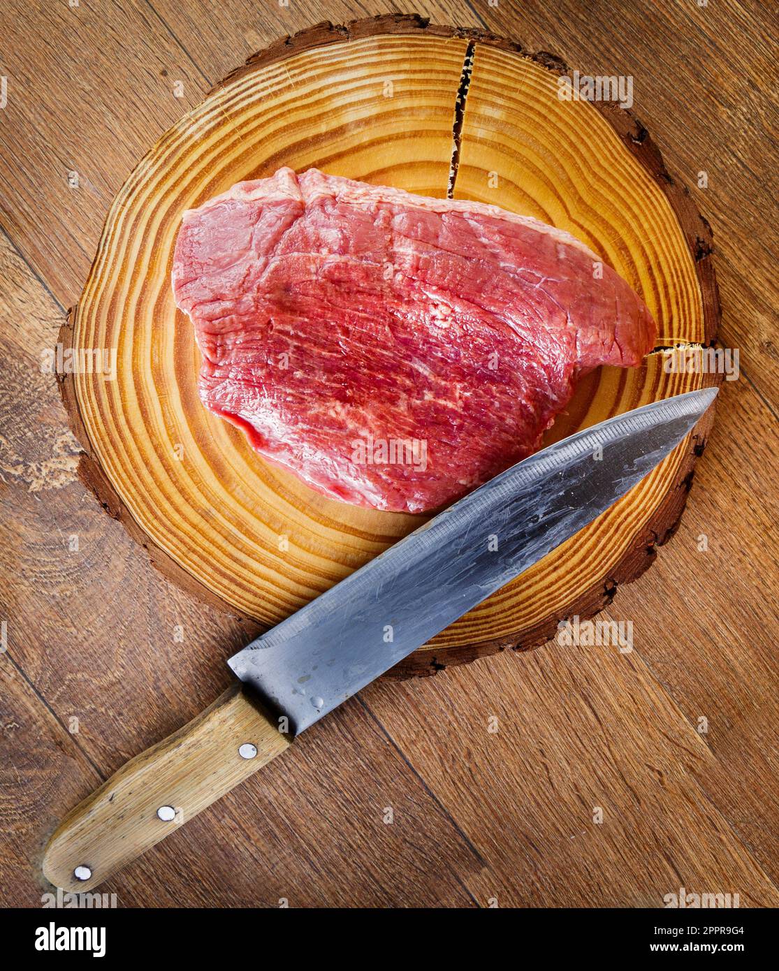 Bistecca di Picanha cruda su sfondo di legno in stile rustico. Coltello sulla barra. Vista dall'alto. Foto Stock