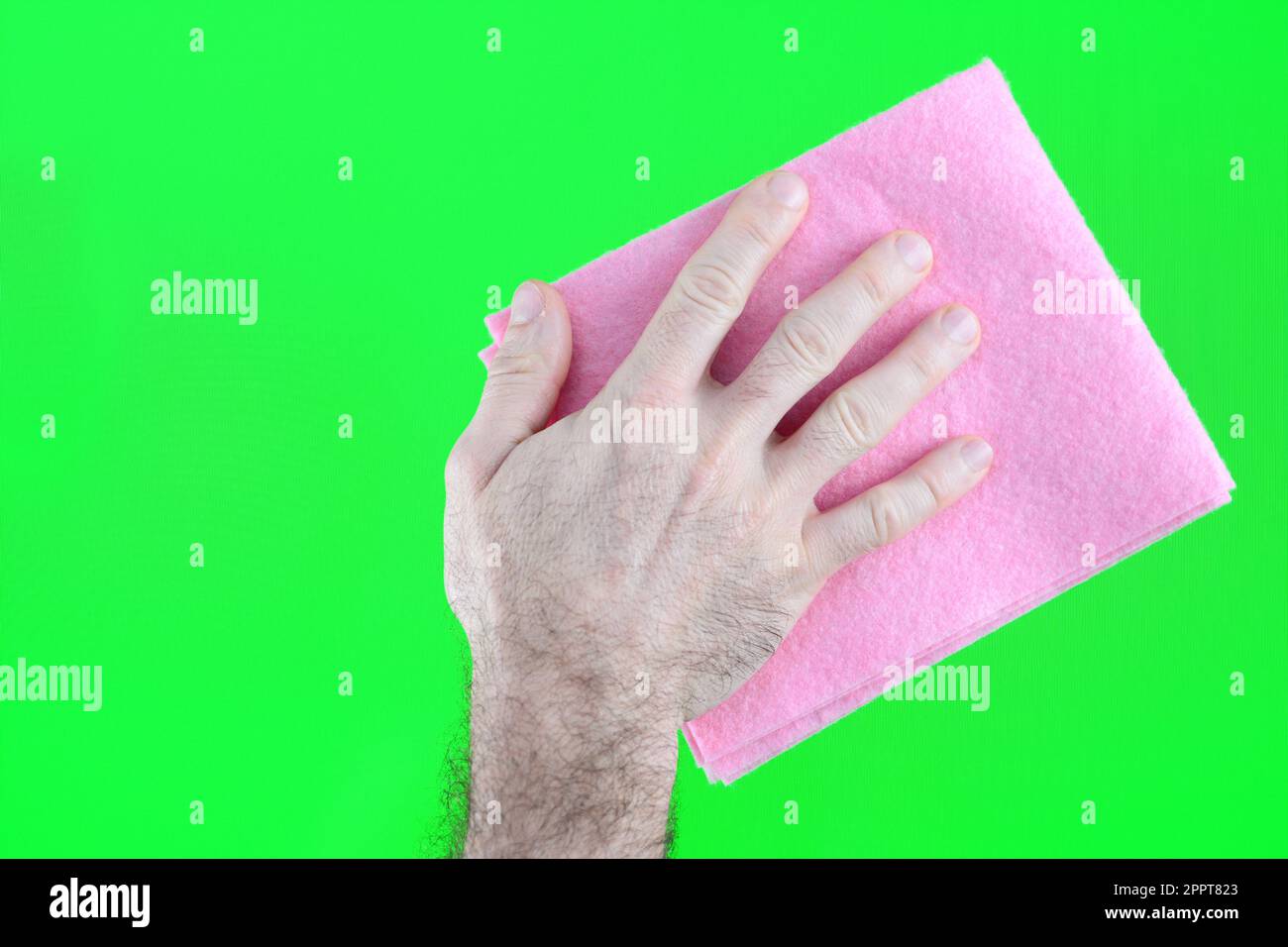 La mano di un uomo in un olio di gomma gialla lucida la superficie di legno del tavolo, il pavimento con uno straccio rosa. Azienda di pulizia, pulizia primaverile a casa. Concetto finitura lucidare mobili Foto Stock