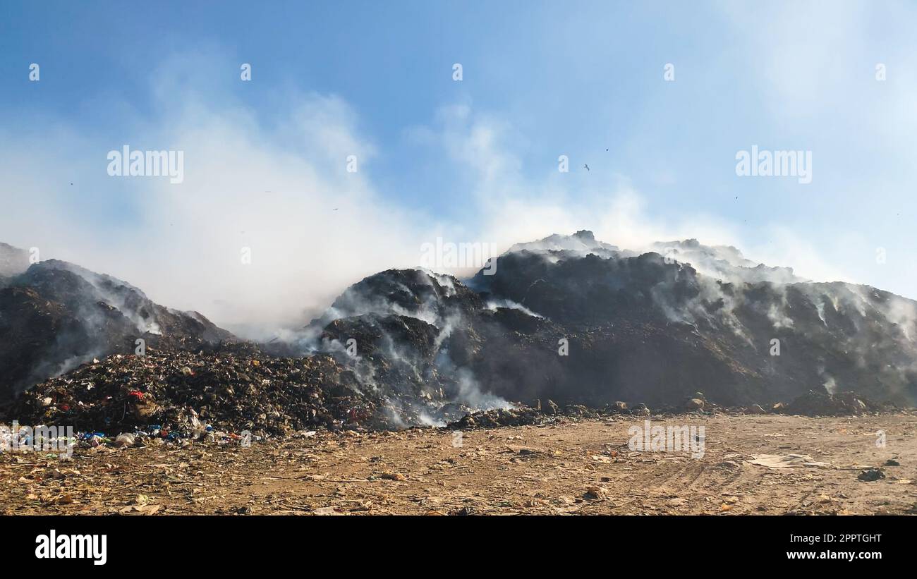 Cumulo di rifiuti in discarica o in discarica che rilascia fumo tossico nell'ambiente e nell'aria inquinante Foto Stock