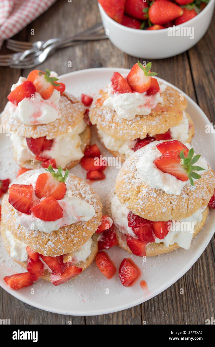 Dessert alle fragole con tradizionali tortine inglesi con panna montata alla vaniglia e fragole marinate su tavola di legno Foto Stock