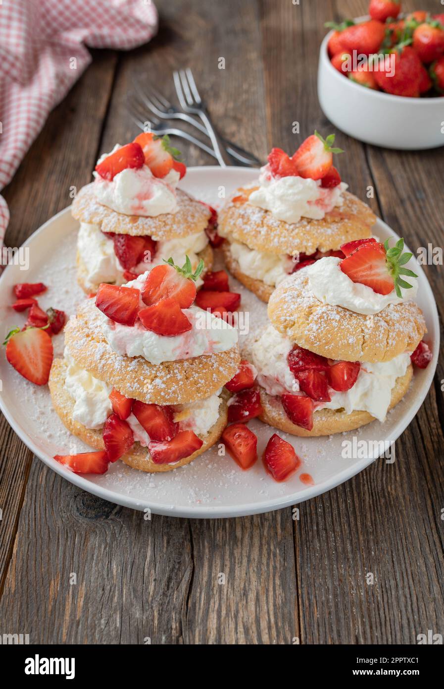 Dessert alle fragole con tradizionali tortine inglesi con panna montata alla vaniglia e fragole marinate su tavola di legno Foto Stock