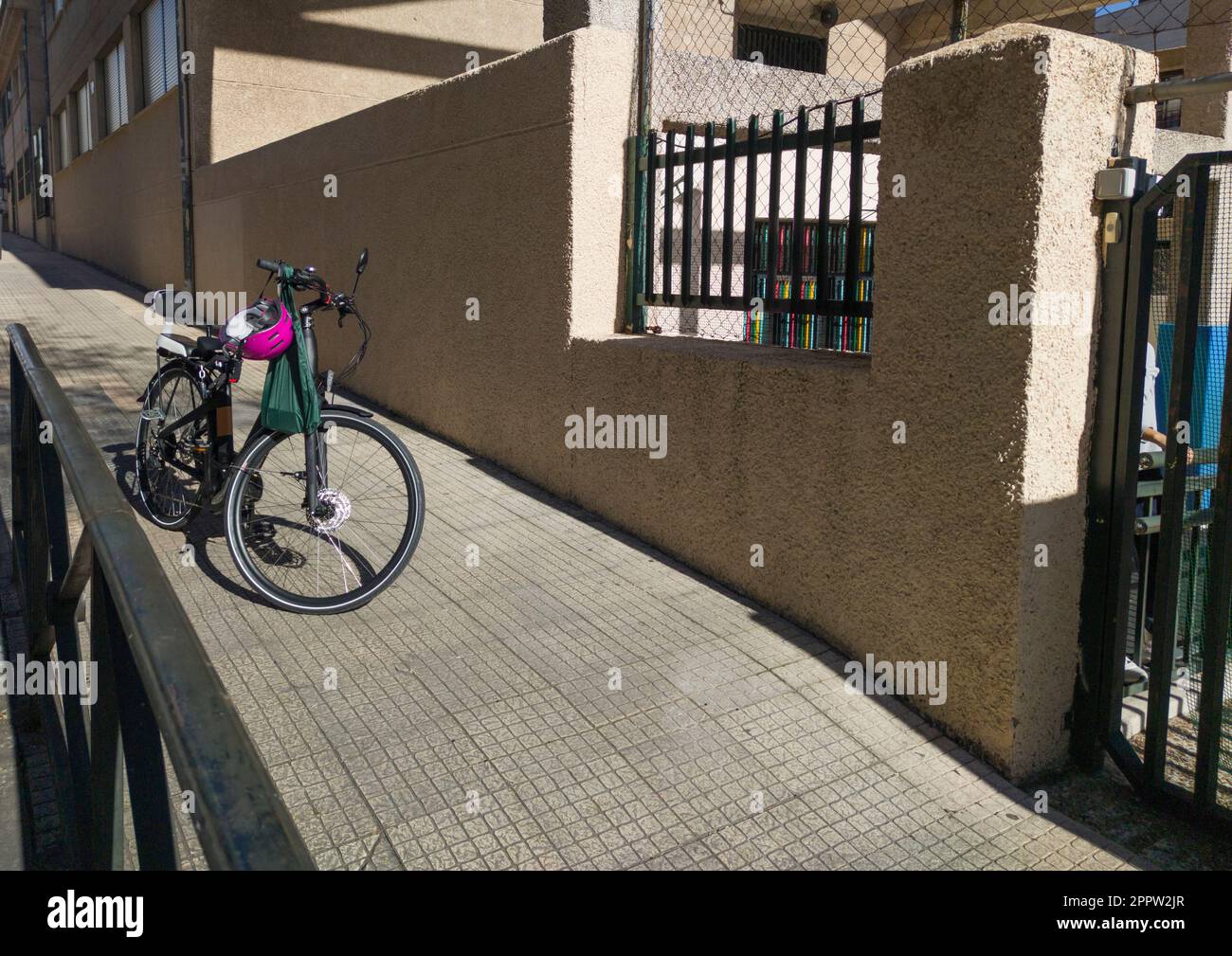 Bici elettrica parcheggiata sul marciapiede, vicino alla porta della scuola primaria. Lascia i bambini a scuola Foto Stock
