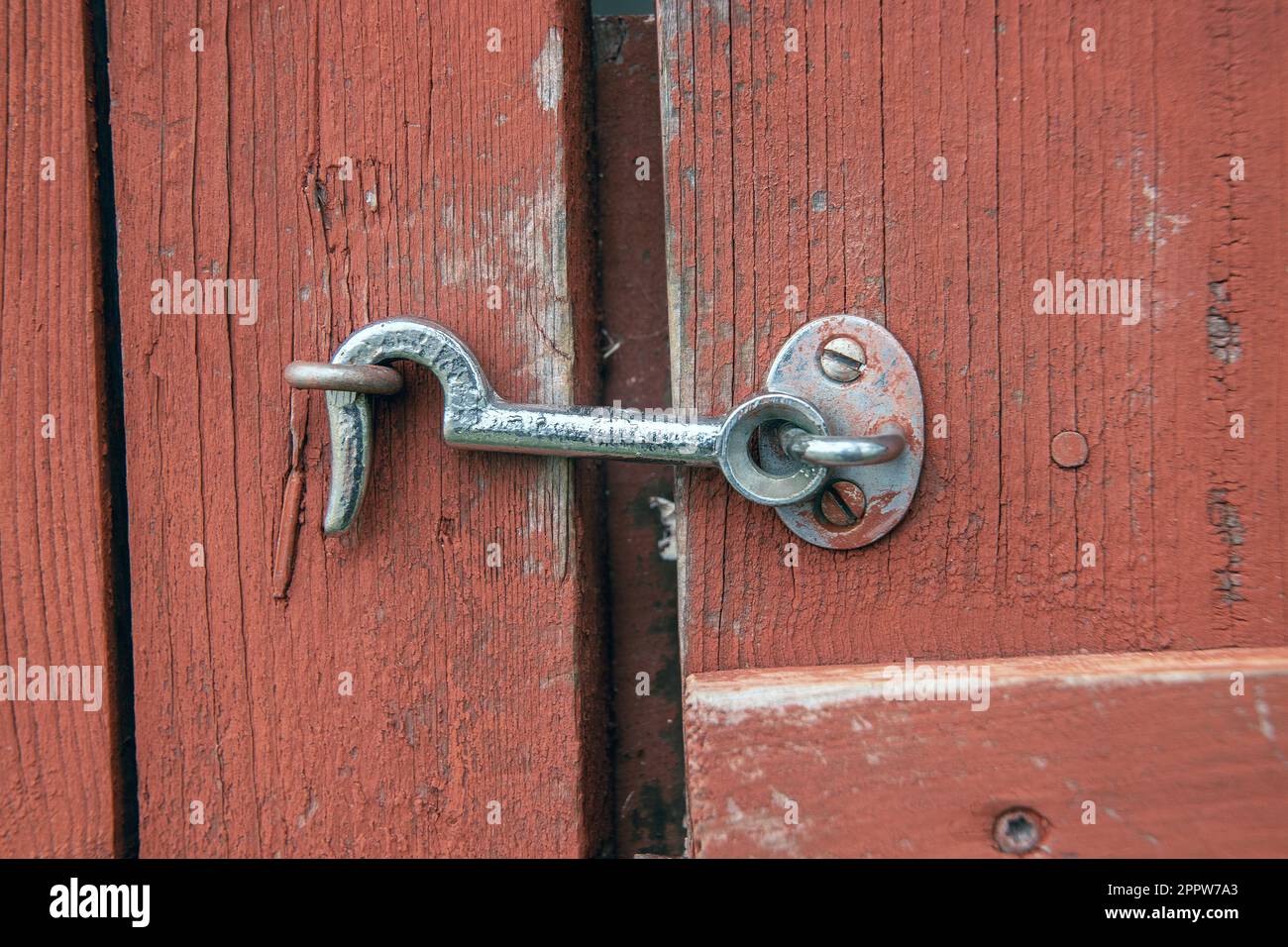 serratura a gancio agganciata al chiodo piegato su una porta di legno rosso Foto Stock