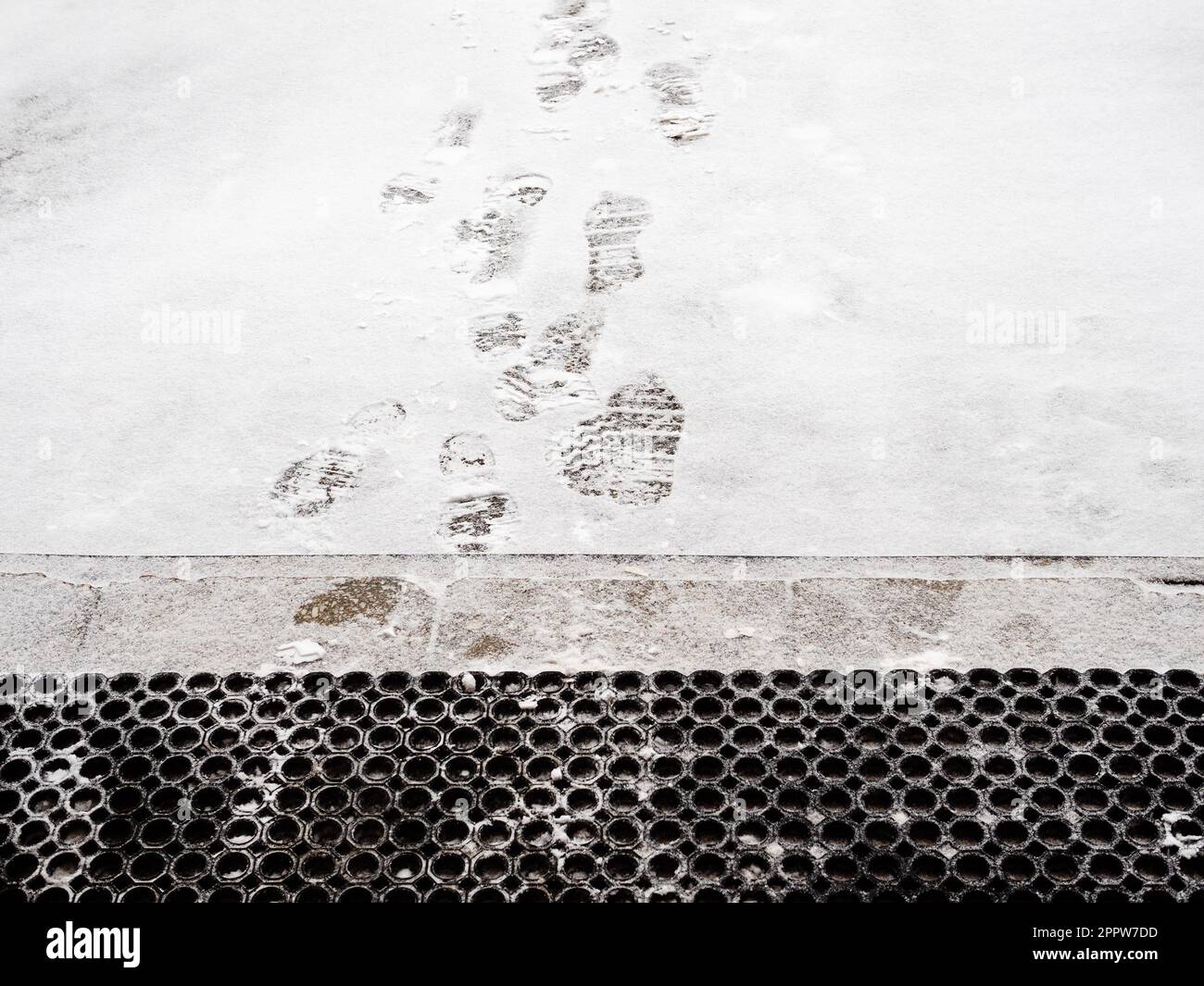 gomma, tappetino e impronte sulla neve appena caduta di fronte al portico dell'edificio residenziale Foto Stock
