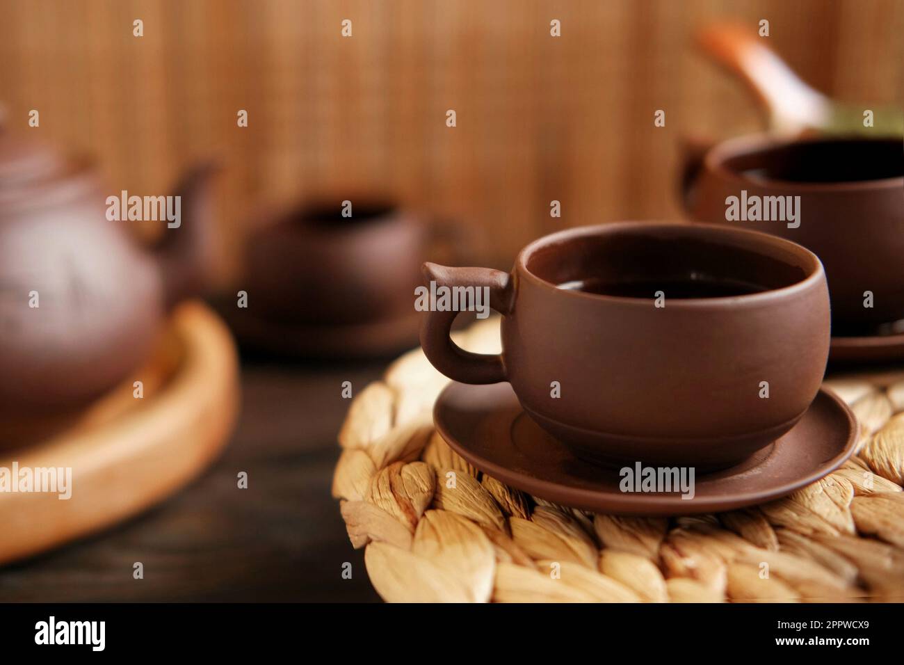 Cerimonia del tè. Tradizionale utensile da tè asiatico, che serve un autentico set. Persona che versa il tè dalla teiera di ceramica marrone a Teacup. Vassoio di bambù. Stile di vita. Noi Foto Stock