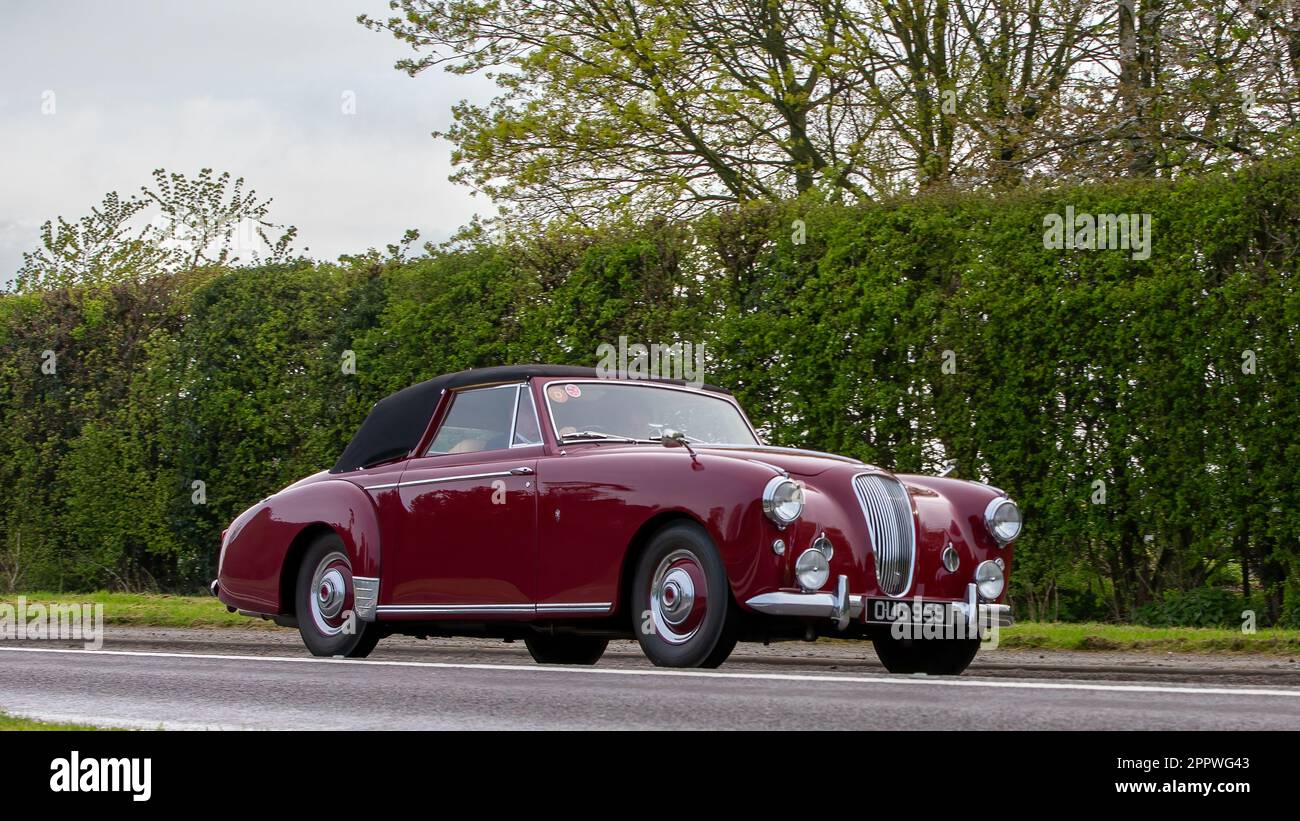 Bicester, Oxon, Regno Unito - Aprile 23rd 2023. 1955 maroon Lagonda auto in viaggio su una strada di campagna inglese Foto Stock
