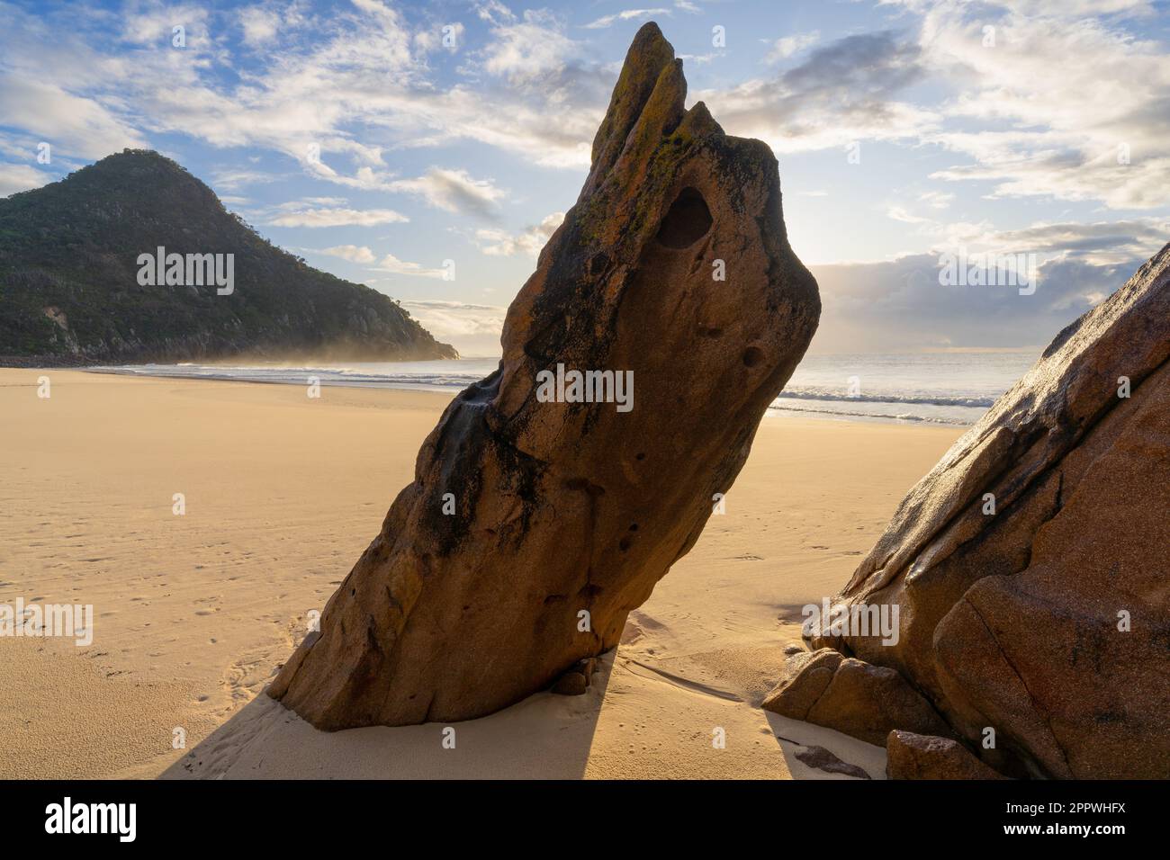 Una grande formazione rocciosa diagonale che si aggira da una spiaggia di sabbia alla luce del mattino a Zenith Beach nel nuovo Galles del Sud, Australia Foto Stock