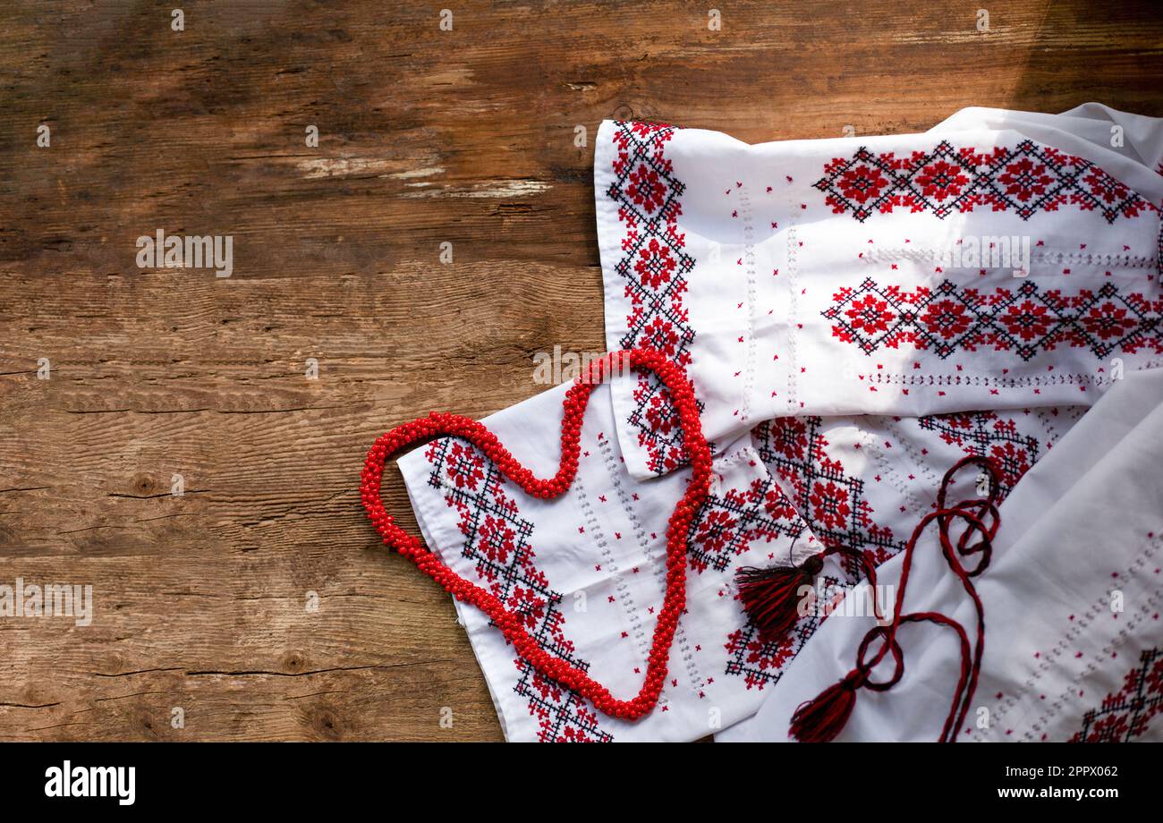 Maglietta bianca ricamata con abiti ucraini. Fili rossi e neri su sfondo di legno. Vyshyvanka è un simbolo dell'Ucraina. Spazio copia ricamo. Cuciture incrociate. Foto Stock