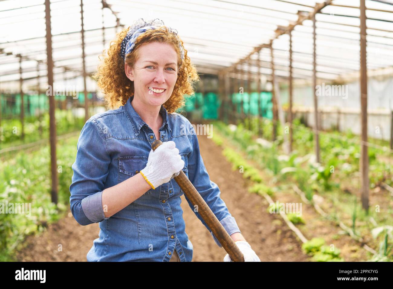 Ritratto di felice contadina che indossa una camicia in denim mentre lavora in fattoria Foto Stock