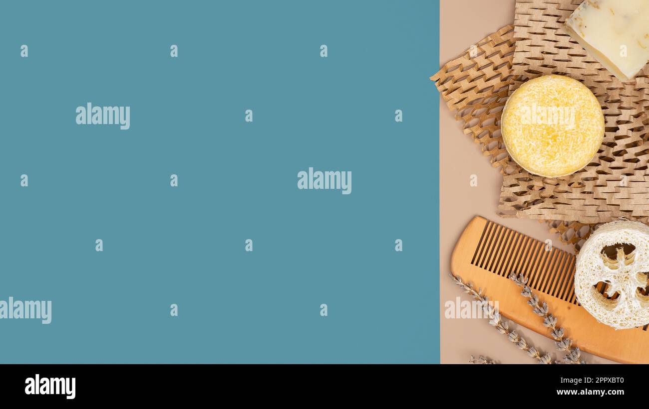 Barra di shampoo solida sostenibile, pettine in legno naturale in spugna Luffa su carta Honeycomb, sfondo blu e marrone. Cura dei capelli ecologica. Zero sprechi Foto Stock