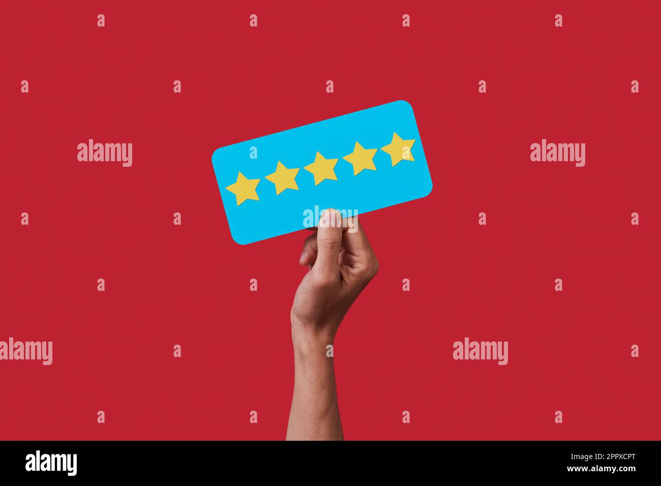 la mano di un uomo tiene un segno blu con cinque stelle, da una scala di valutazione a cinque stelle, su uno sfondo rosso Foto Stock