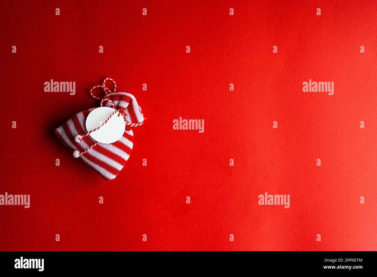 Borsa regalo in maglia rossa e bianca a righe su sfondo rosso brillante Foto Stock