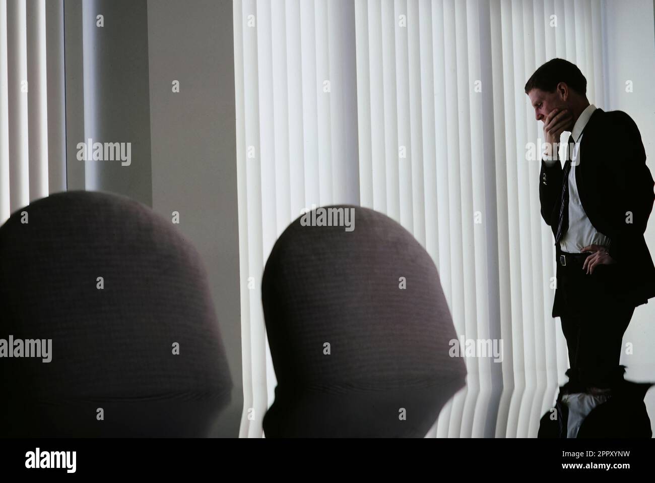 Single Caucasian giovane esecutivo profondo pensiero in piedi da solo nella conferenza room37 Foto Stock