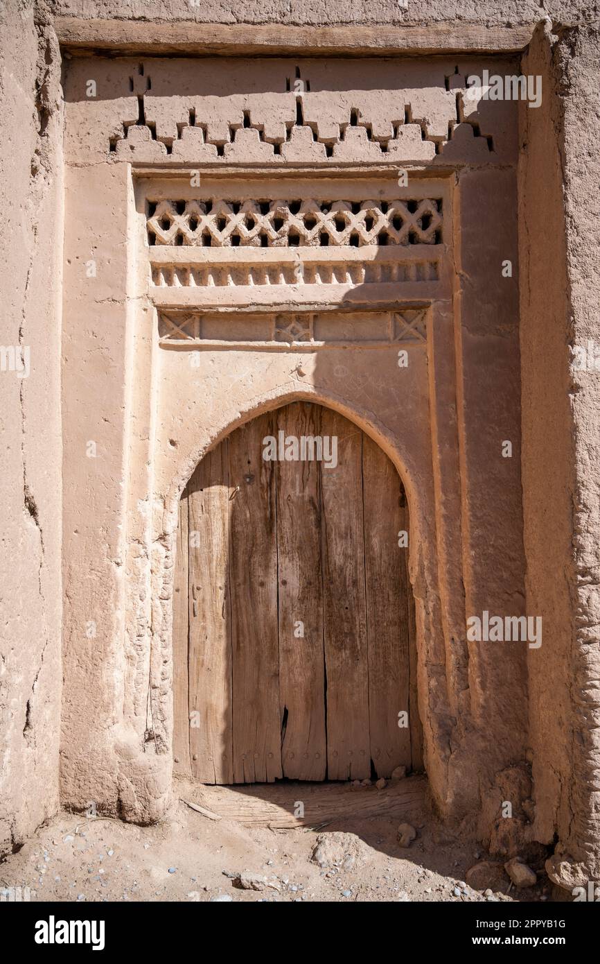 Porta in legno in una casa in mattoni nella vecchia medina di Tinghir, decorata con motivi tradizionali berberi. Foto Stock