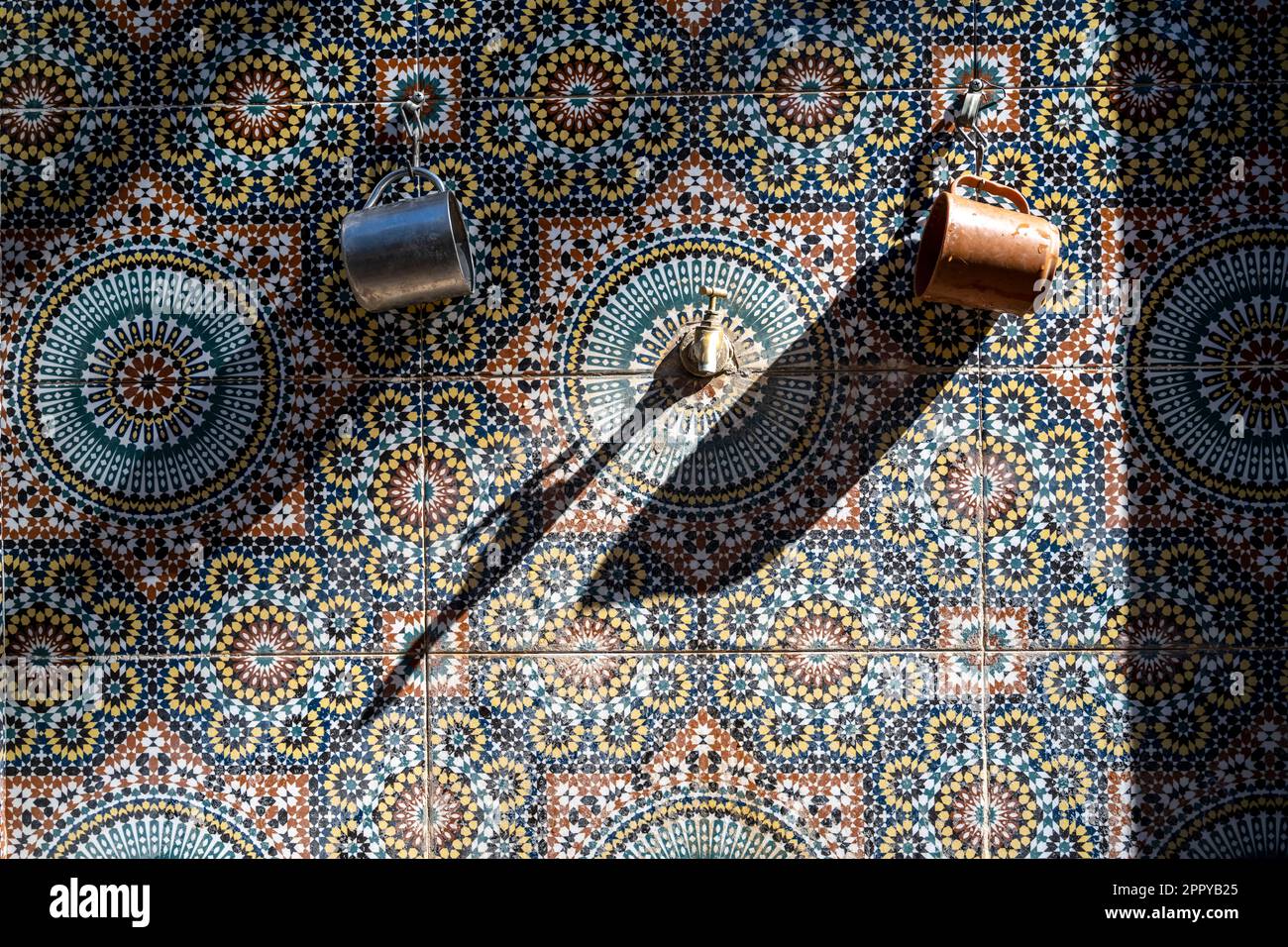 Due calici appesi sulle piastrelle di una fontana decorata. Foto Stock