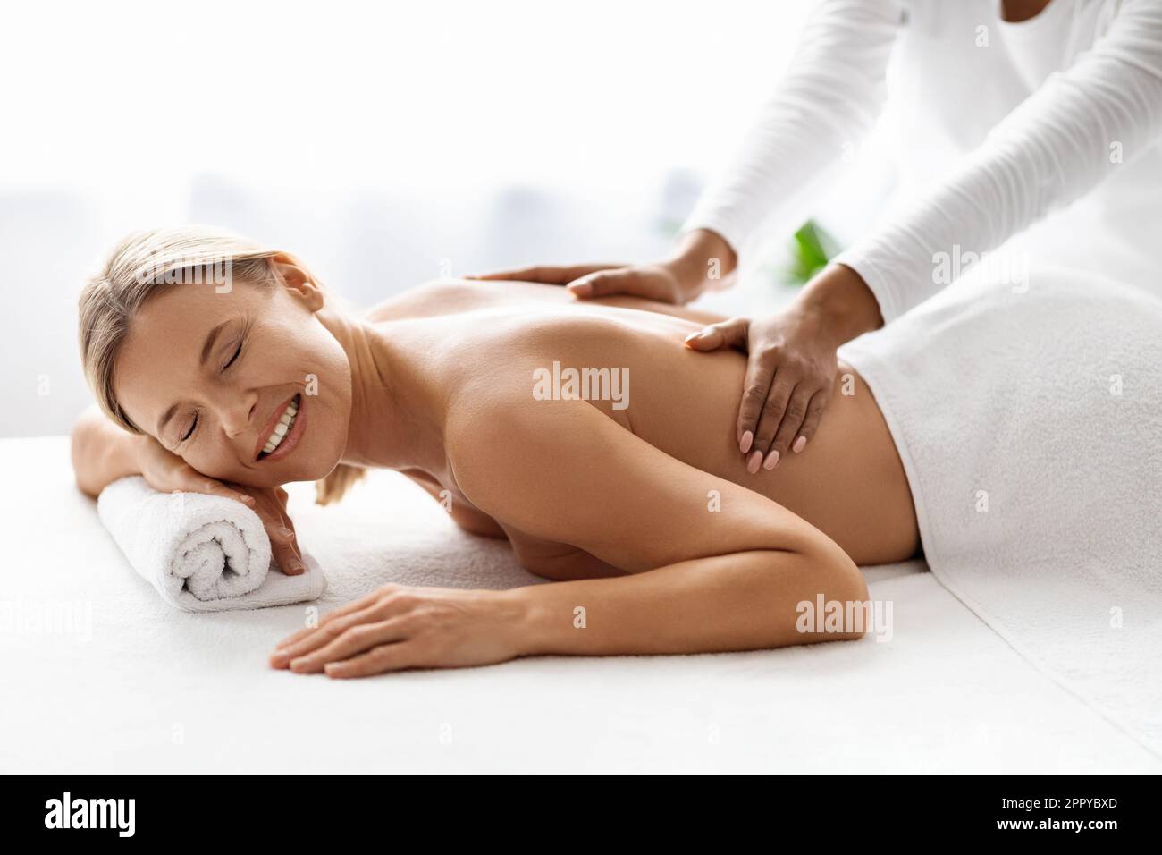 Bella donna di mezza età che riceve un massaggio rilassante alla schiena da un terapista professionista Foto Stock