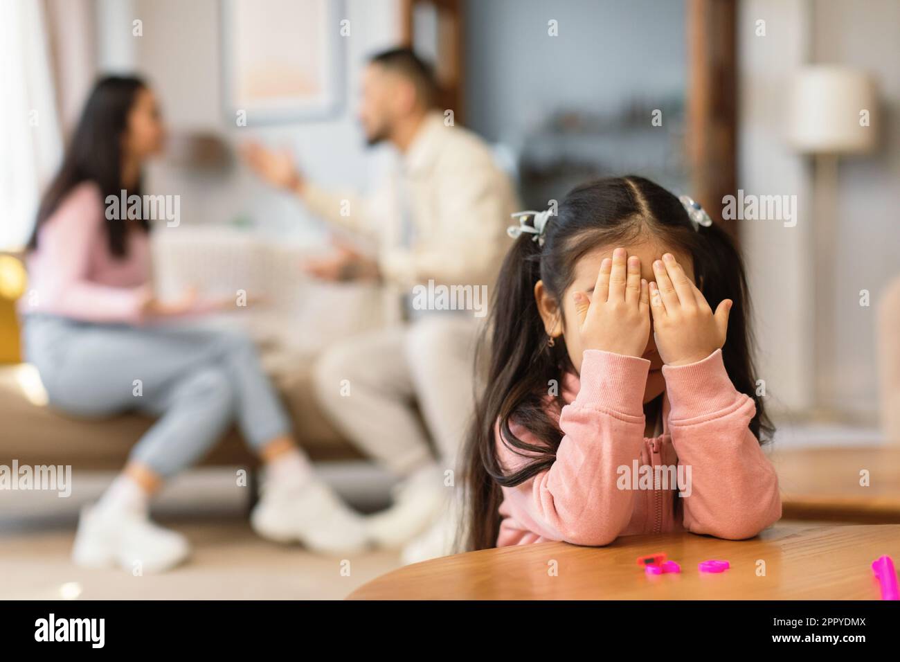 Asian Girl piangendo occhi coperti mentre i genitori hanno litigare Indoor Foto Stock