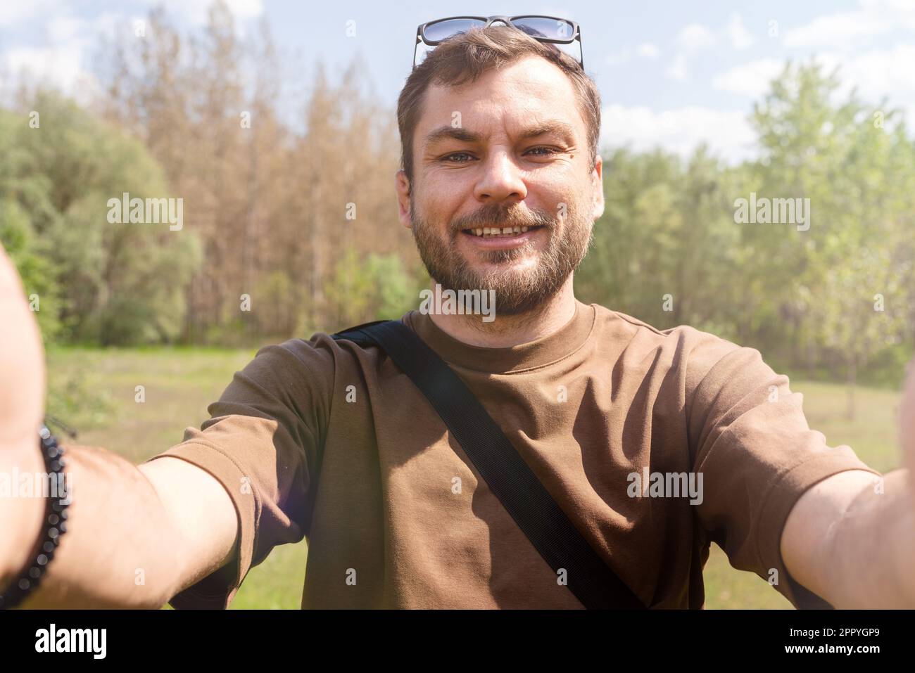 L'uomo prende un selfie all'aperto nel parco utilizzando il suo telefono cellulare. Foto Stock