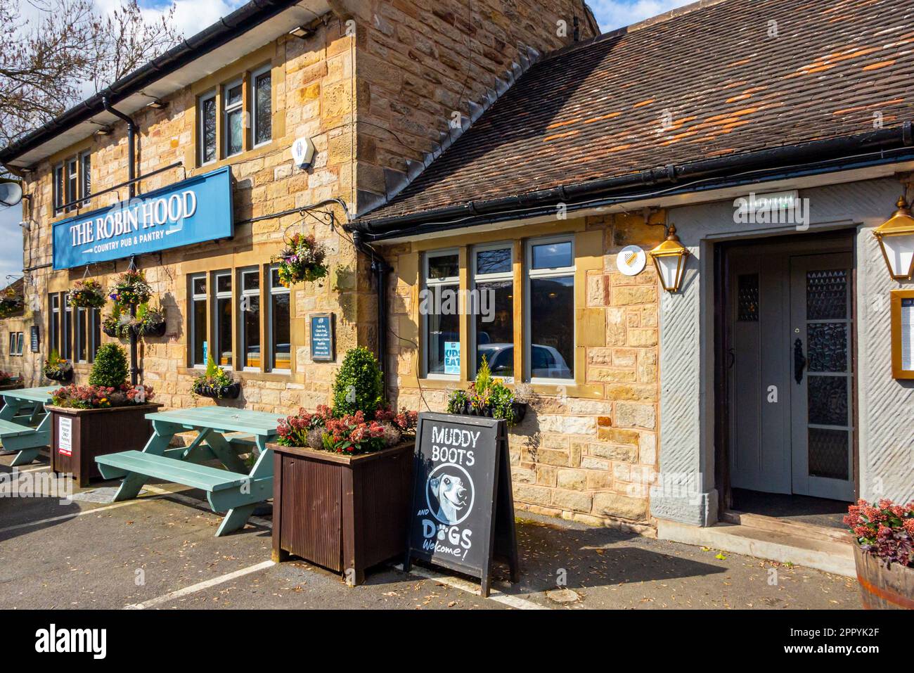 Vista esterna del Robin Hood, pub di campagna vicino a Baslow, nel Derbyshire Peak District, Inghilterra, Regno Unito, con il cartello di benvenuto Muddy Boots and Dogs all'esterno. Foto Stock