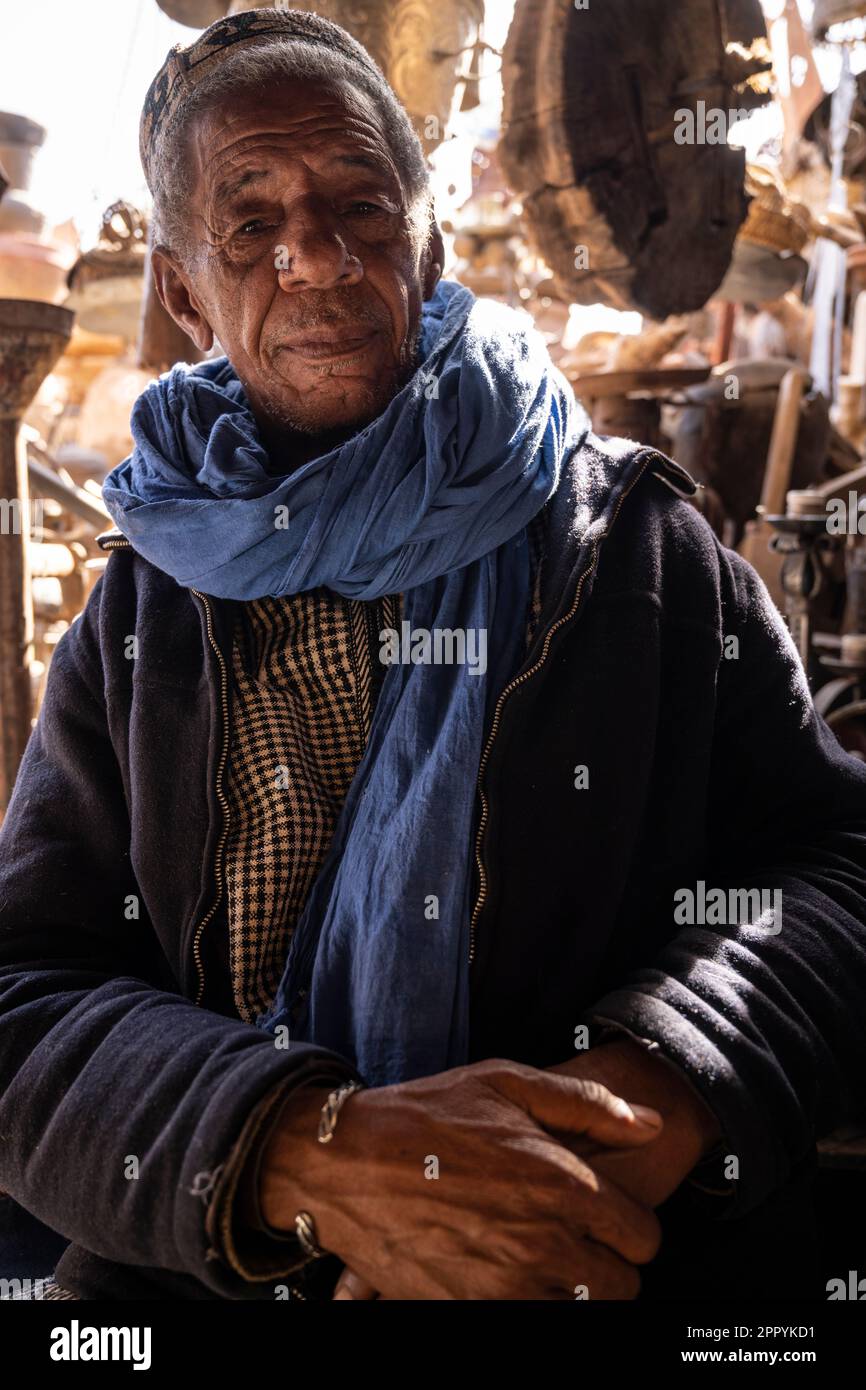 Ritratto di un vecchio berbero vestito con abiti tipici del suo gruppo etnico alla porta del suo negozio. Foto Stock