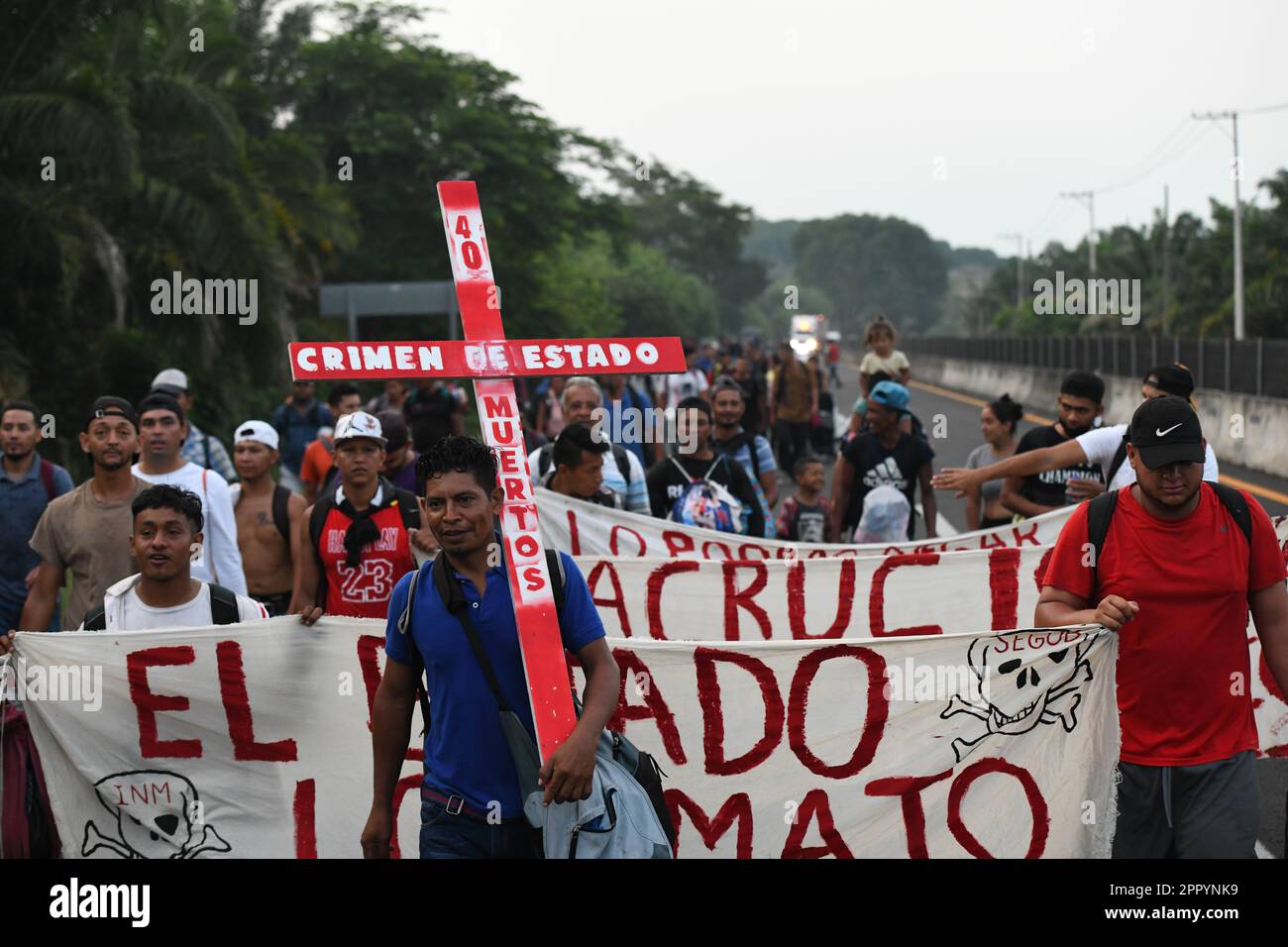 Huehuetan, Messico. 25th Apr, 2023. '40 morti - crimine di stato,' è scritto sulla croce portata da un migrante come egli cammina attraverso il Messico. Le circa 3.000 persone, soprattutto dell'America centrale, che si sono insediate a nord domenica, vogliono richiamare l'attenzione sulla loro situazione e chiedere giustizia dopo la morte di 40 migranti in una struttura per l'immigrazione. Credit: Isaac Guzman/dpa/Alamy Live News Foto Stock