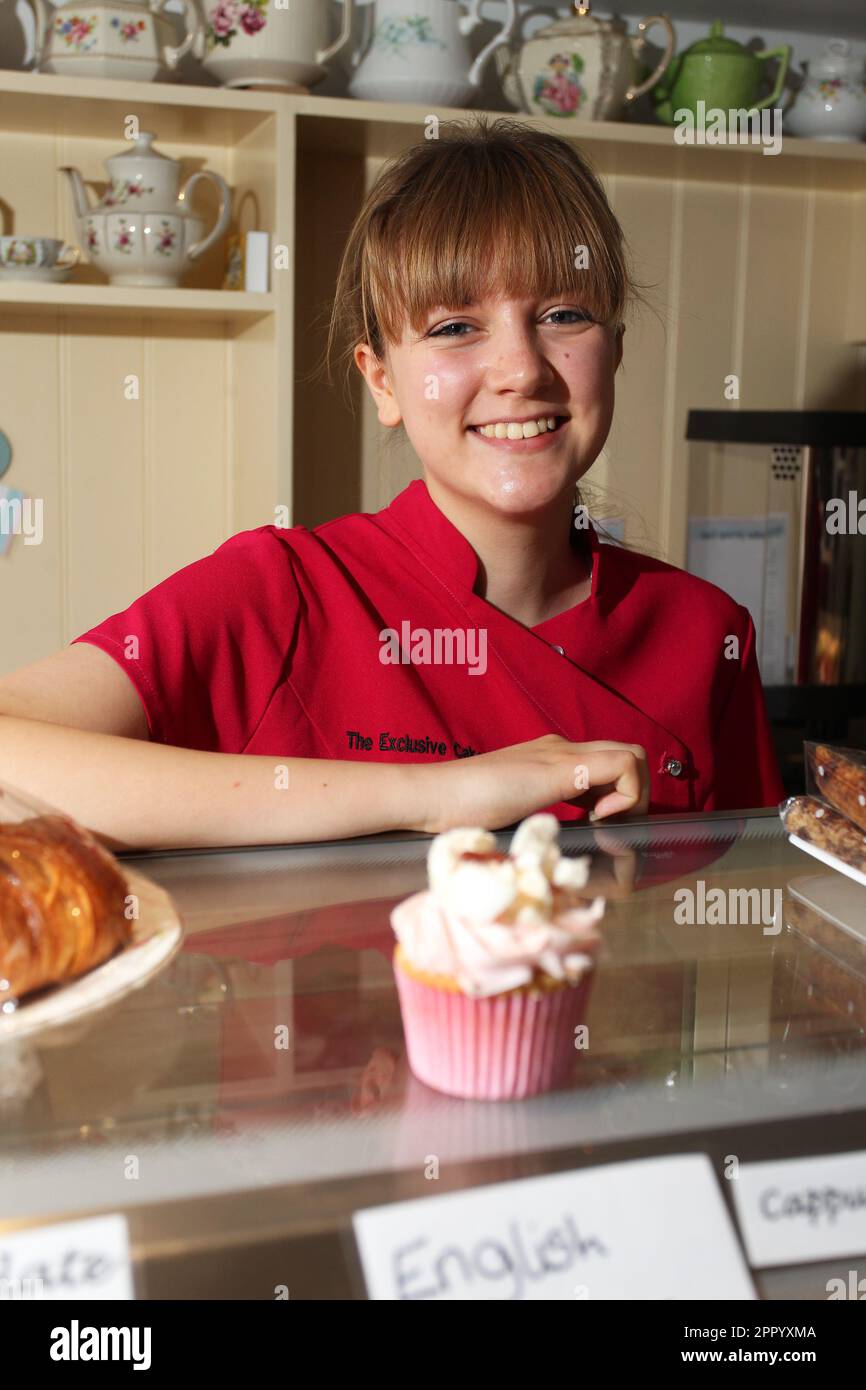 Ragazza carina che vende cupcake in una pasticceria a Chichester, West Sussex, Regno Unito. Foto Stock