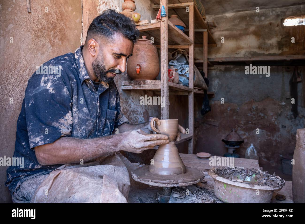 Artigiano che produce un recipiente in ceramica su un banco con una ruota di vasaio. Foto Stock