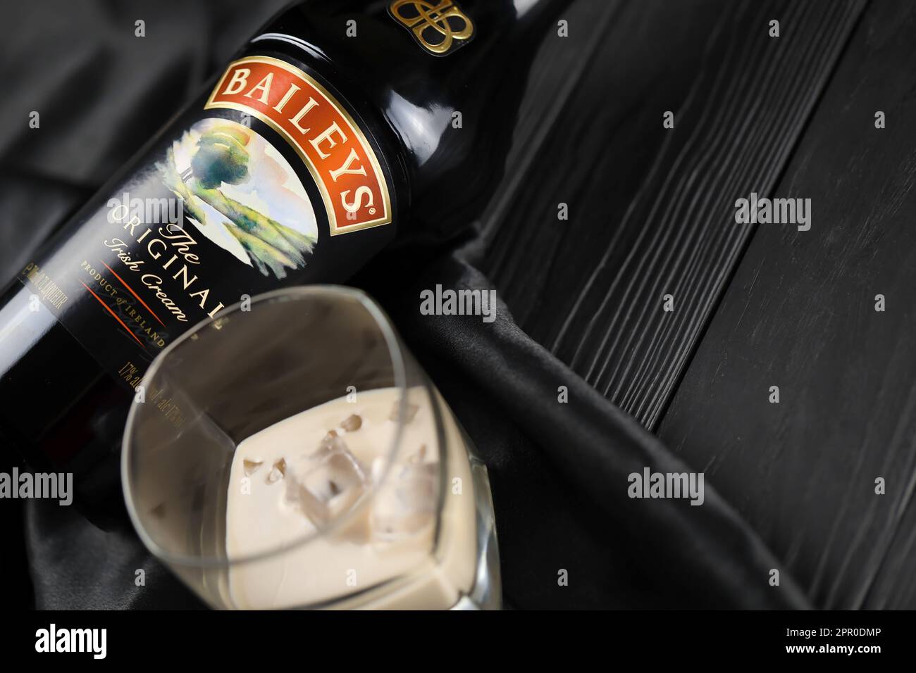 KIEV, UCRAINA - 4 MAGGIO 2022 Baileys bottiglia di alcool originale su tavolo di legno con tessuto nero sullo sfondo. Produzione di alcool Elite Foto Stock