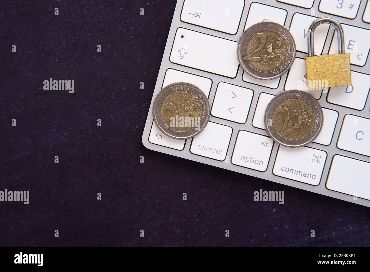 Lucchetto chiuso su alcune monete in euro sul telaio di un computer portatile. Mantenete al sicuro i nostri risparmi. Spazio per la copia del testo. Sfondo scuro. Foto Stock