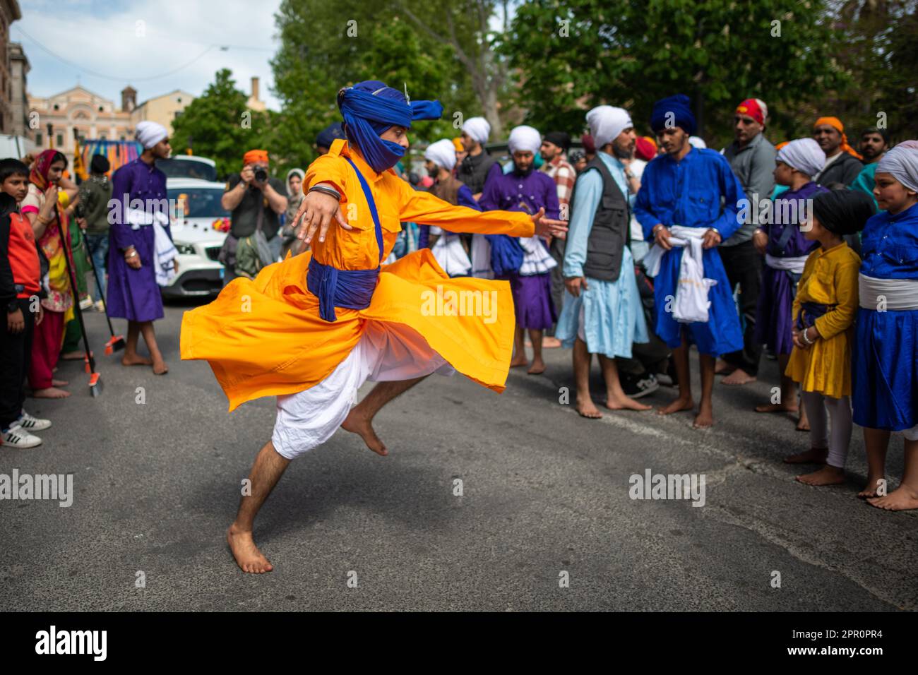 Un ragazzo sikh si esibisce durante la processione per il Vaisakhi Nagar Kirtan nel distretto di Esquiline. Nei giardini di Piazza Vittorio, i Sikh di Roma cantavano canzoni di Shabad (inni divini), pregavano e rinviavano omaggio al Granth Sahib, il libro sacro. Con il Nagar Kirtan, che i Sikh di tutto il mondo fanno nel mese di Vaisaki (verso aprile), attraversando le strade del quartiere, cantando inni sacri, portarono il messaggio di Dio ad altre comunità. A Pessina Cremonese sorge il secondo tempio Sikh più grande d'Europa. Una delle unità Sikh dell'VIII Armata Britannica si distingueva Foto Stock