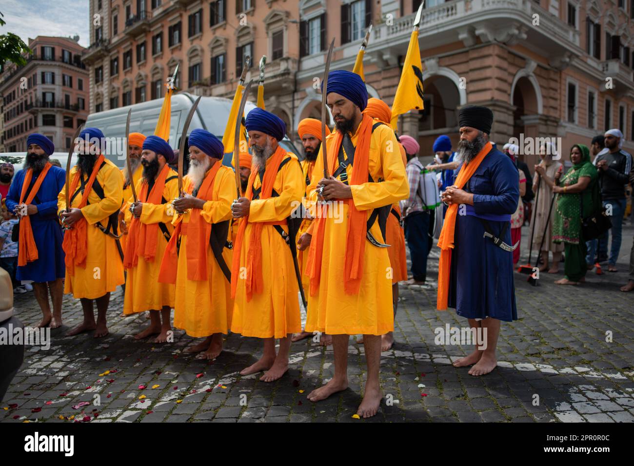 Uomini Sikh con il kirpan, scortano il Granth Sahib durante la processione per il Vaisakhi Nagar Kirtan nel distretto di Esquiline. Nei giardini di Piazza Vittorio, i Sikh di Roma cantavano canzoni di Shabad (inni divini), pregavano e rinviavano omaggio al Granth Sahib, il libro sacro. Con il Nagar Kirtan, che i Sikh di tutto il mondo fanno nel mese di Vaisaki (verso aprile), attraversando le strade del quartiere, cantando inni sacri, portarono il messaggio di Dio ad altre comunità. A Pessina Cremonese sorge il secondo tempio Sikh più grande d'Europa. Una delle unità Sikh del V britannico Foto Stock