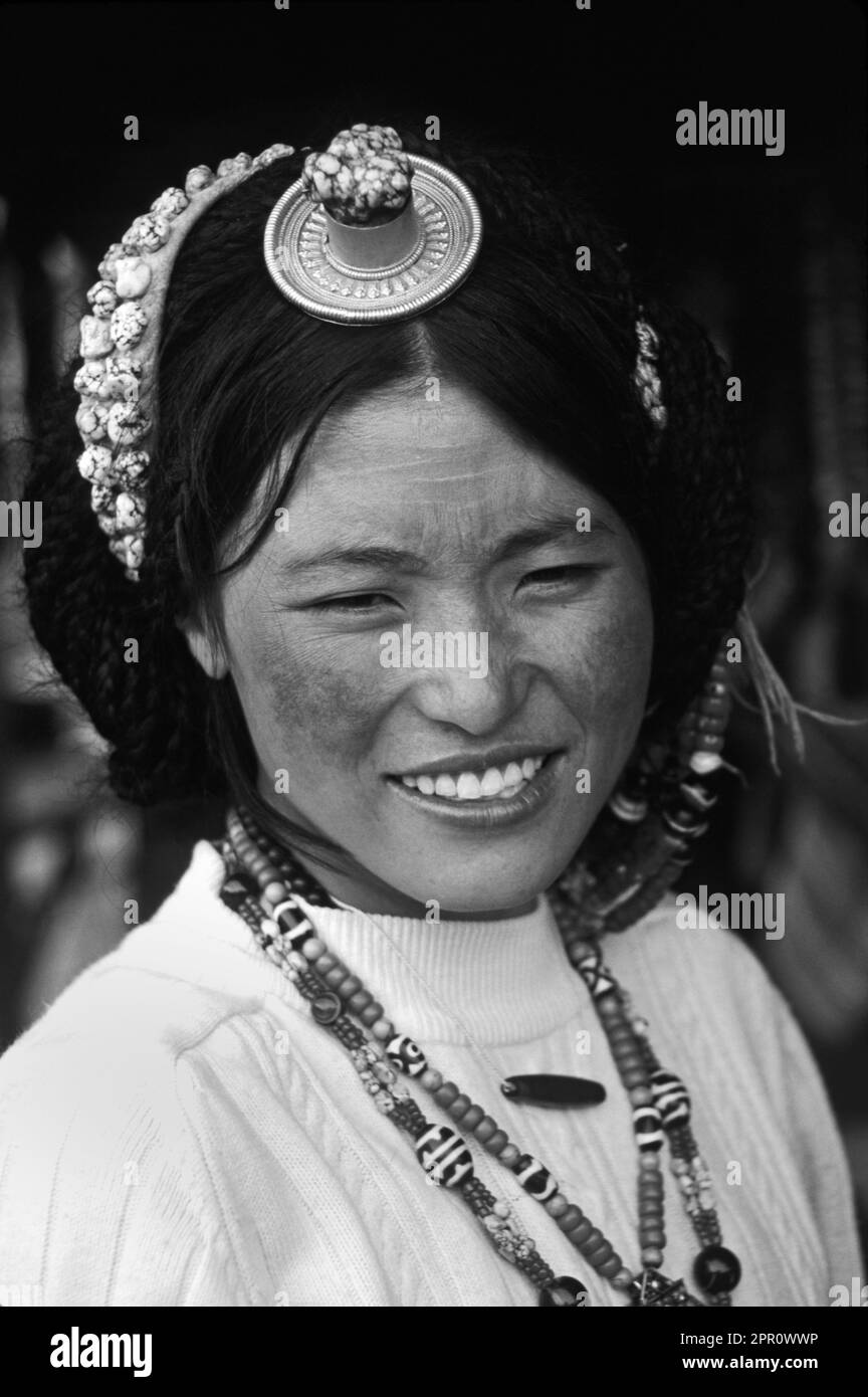 UNA BELLEZZA TIBETANA INDOSSA TURCHESE, CORALLO, PIETRE Z E UN PEZZO DI ORO E CORALLO CAPELLI - LHASA, TIBET Foto Stock