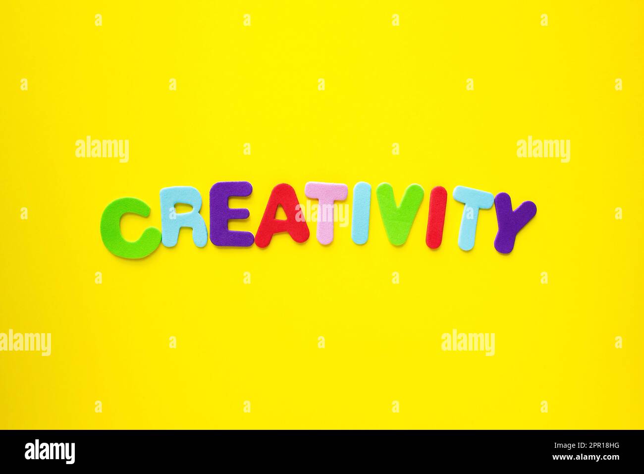 Parola creativa con lettere alfabetiche colorate isolate su sfondo giallo come intestazione banner con spazio copia. Foto Stock
