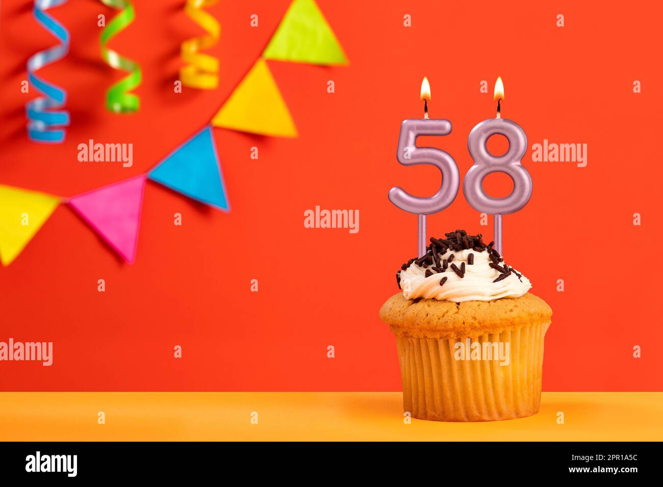 Torta di compleanno con candela numero 58 - sfondo arancione frizzante con bunting Foto Stock